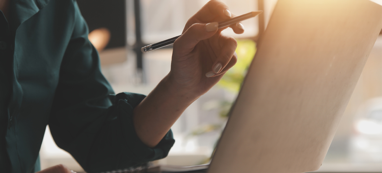 person pointing towards monitor with pen in hand