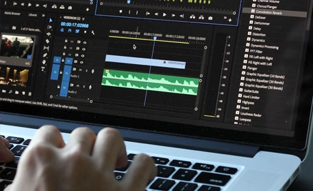 A person editing footage on a laptop using Adobe Premiere Pro software.