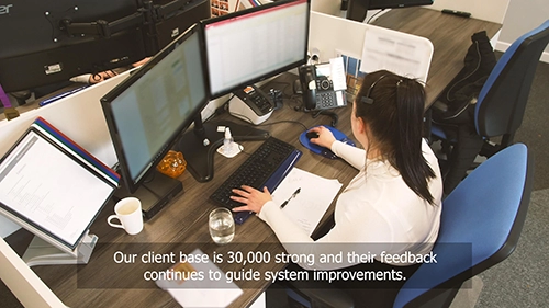 A Blue Frontier worker at their desk working with subtitles placed over the image.