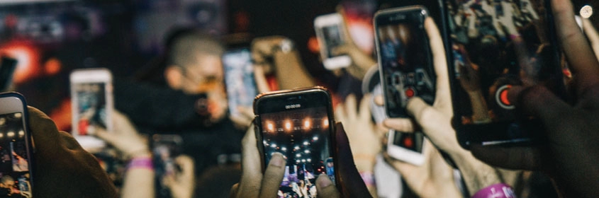 Lots of people in a crowd holding up their mobile phones to record a live event.