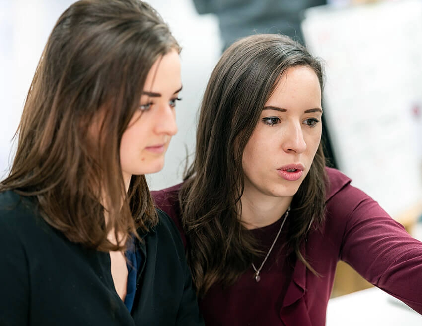 Two women in a serious discussion looking off camera.