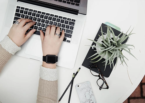 Writing a blog. A woman typing on a laptop.