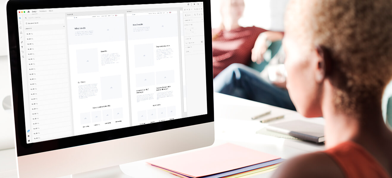 A woman looking at a digital website wireframe on desktop.