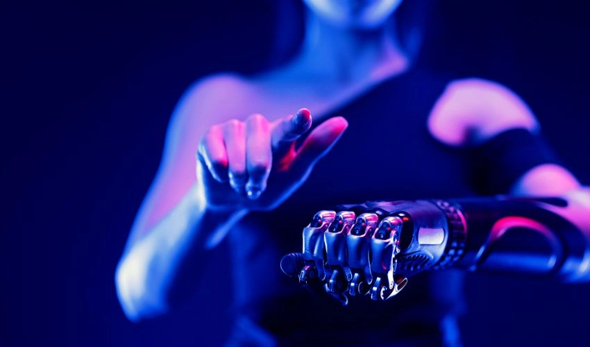 A photo of a woman using a specially-created bionic arm whilst wearing a virtual reality headset.