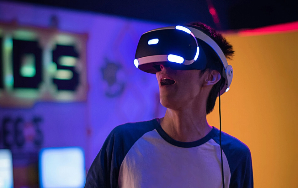 A person gasping in awe whilst wearing a virtual reality headset in a quirky, neon-coloured gaming environment.