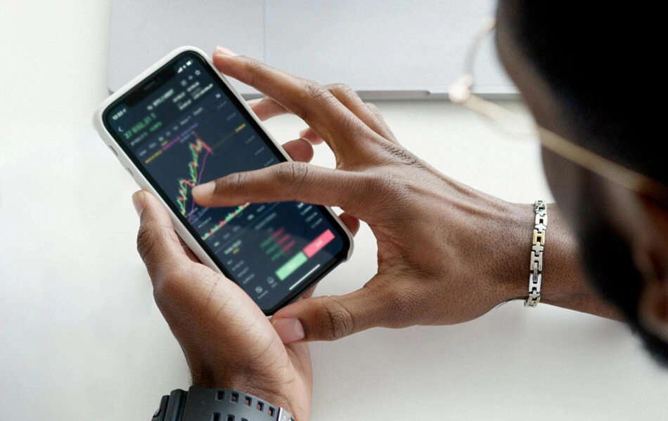 A birds-eye view of a businessman holding his phone and analysing stocks data via an app.