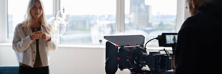 Video camera setup focusing on a woman in a bright studio