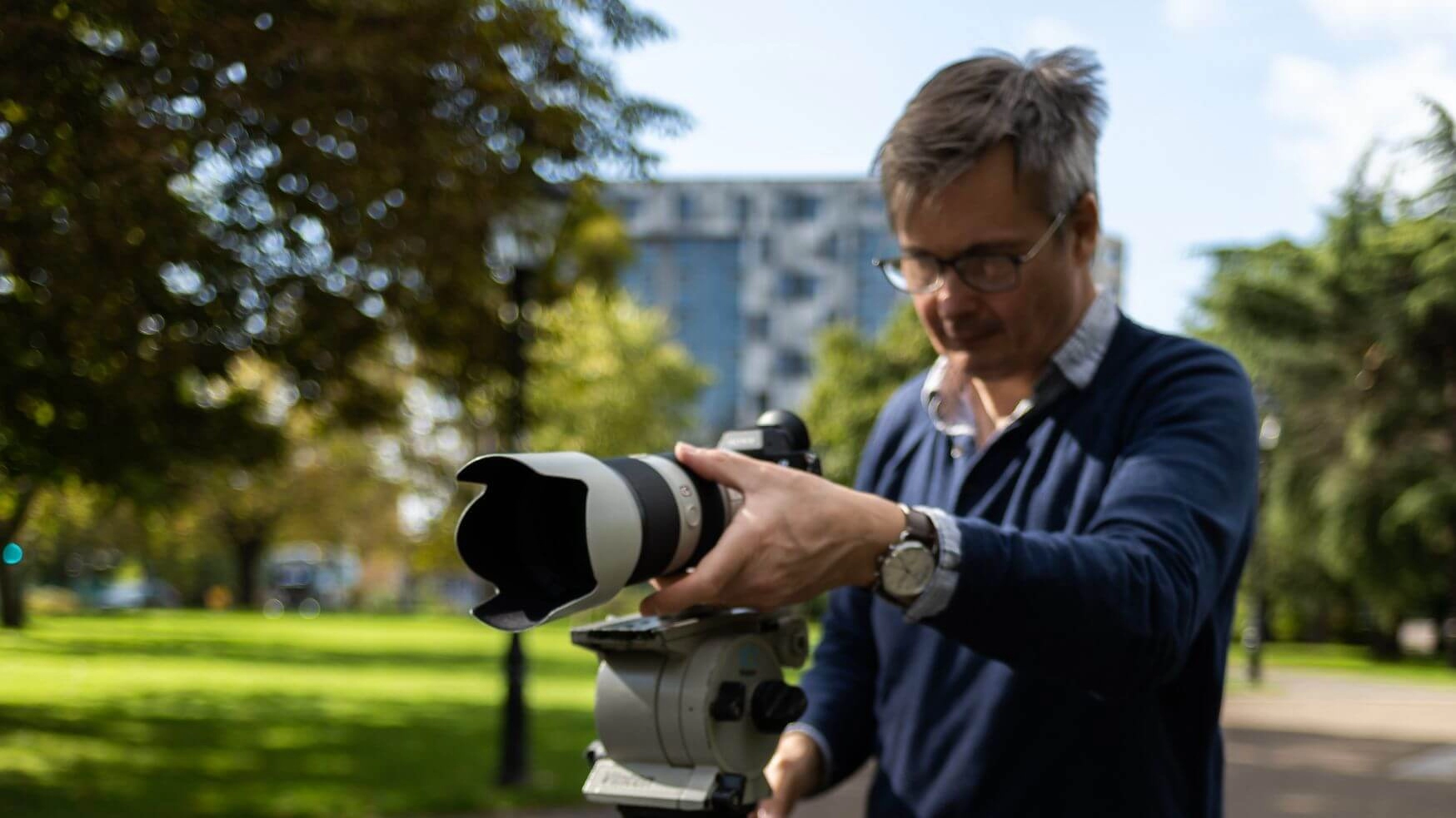 Photo of a man looking into a camera on a tripod.