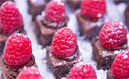 Brownies with raspberries and icing sugar on top.