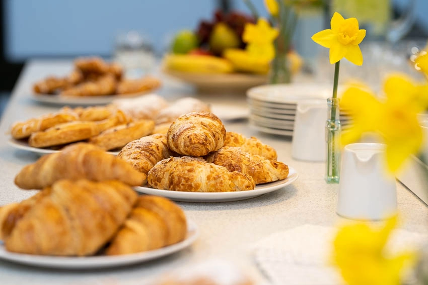 A table spread of pastries and decorative daffodils in small vases.