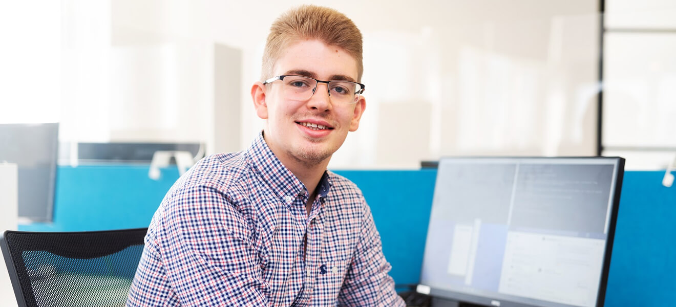 A Blue Frontier staff member smiling by desktop computers.