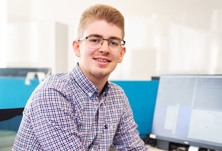 A Blue Frontier staff member smiling by desktop computers.