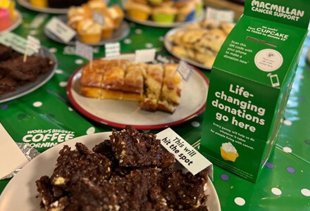 Macmillan donation box next to plates of sweet treats.