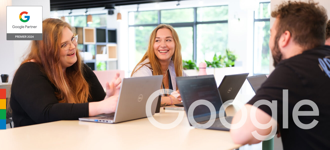 The team smiling and conversing at a table with laptops.