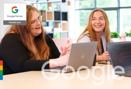 The team smiling and conversing at a table with laptops.