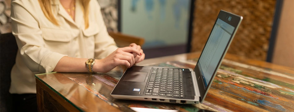 A woman's hand hovers over the laptop.