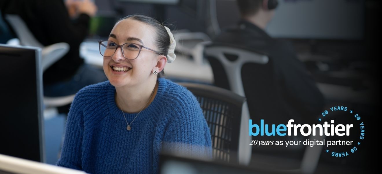 a young employee smiling up at the camera in a bustling and modern open-plan office