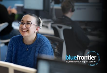 a young employee smiling up at the camera in a bustling and modern open-plan office