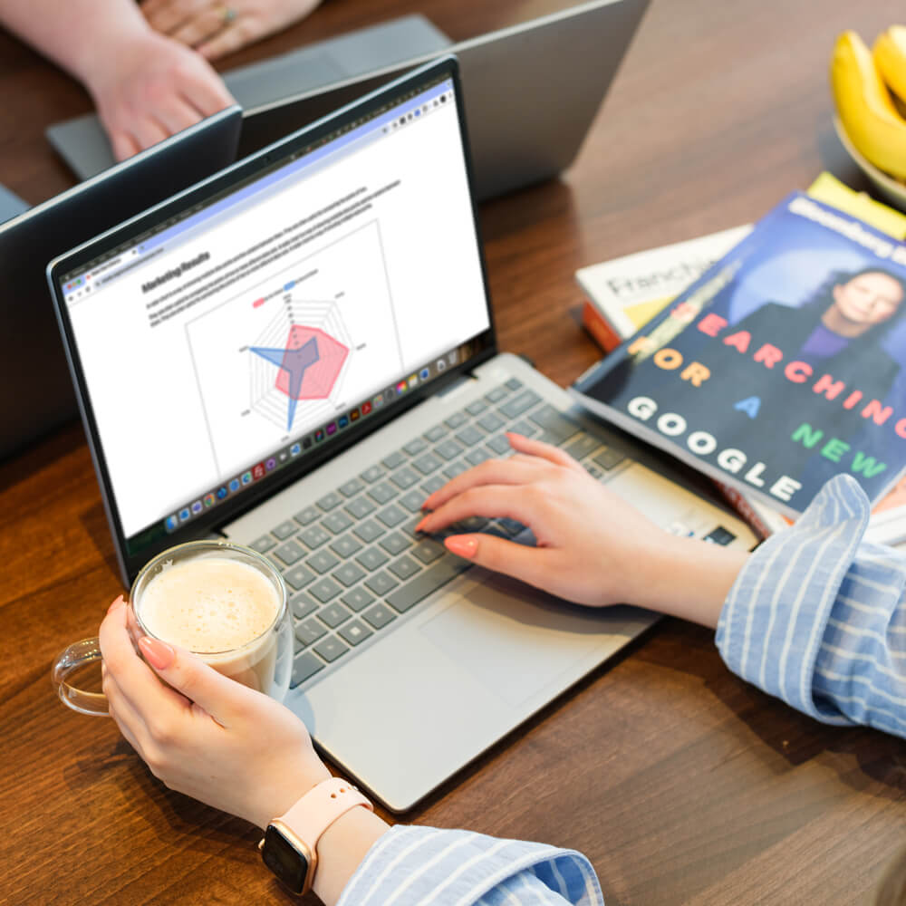 two people sit at a meeting room looking at a laptop showing various data graphs two people sit at a meeting room looking at a laptop showing various data graphs