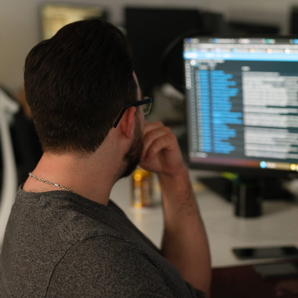 a man looks at code on his computer screen in a dimly lit room a man looks at code on his computer screen in a dimly lit room