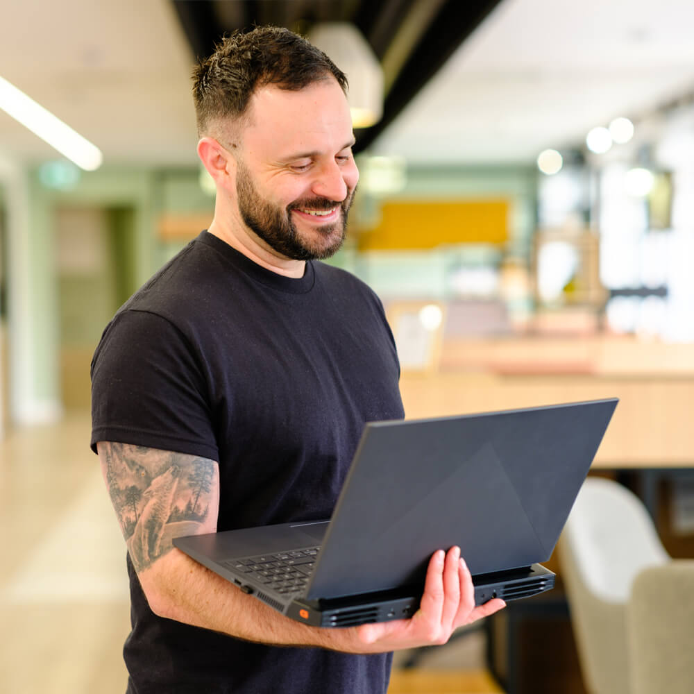 a cyber security expert holding a laptop and smiling