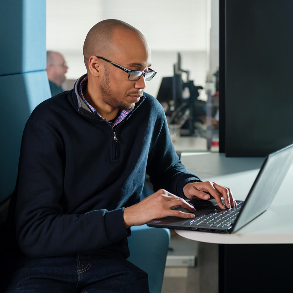 a cyber security expert typing on a laptop in a modern office space