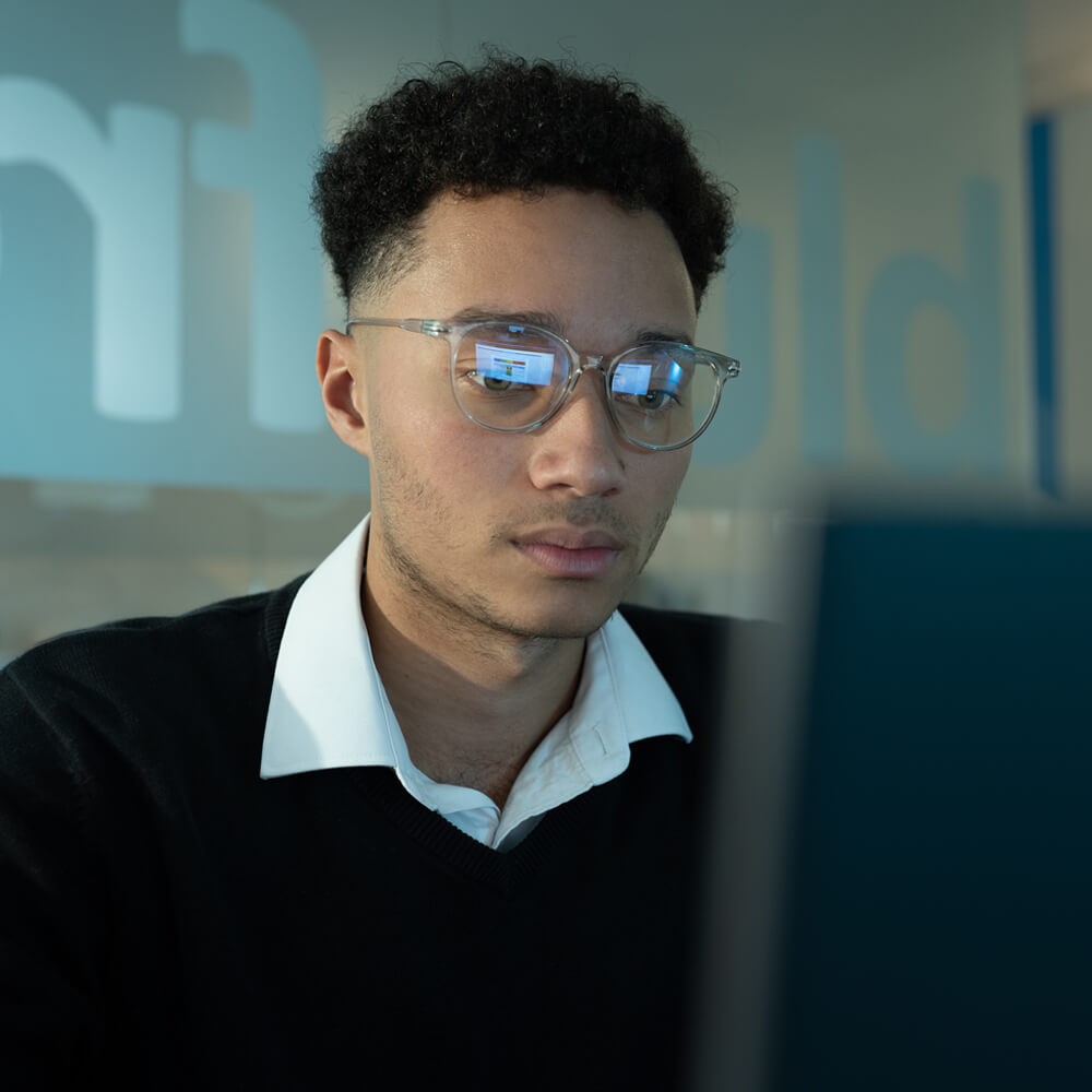 an IT technician analysing data on a laptop in a dimly lit office space