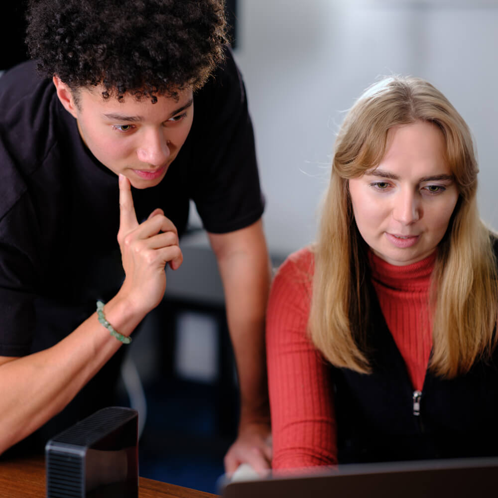 two colleagues looking at a laptop analysing data together